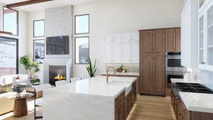 Kitchen with double oven, a large fireplace, sink, and light hardwood / wood-style floors