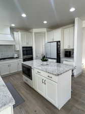 Kitchen featuring white cabinets, light hardwood / wood-style flooring, and white fridge