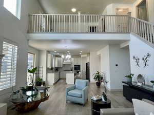 Living room featuring an inviting chandelier, light wood-type flooring, sink, and a high ceiling