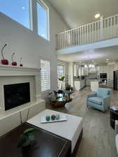 Living room featuring light hardwood / wood-style floors, a high ceiling, and an inviting chandelier