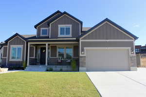 Craftsman inspired home featuring a garage, a porch, and a front yard