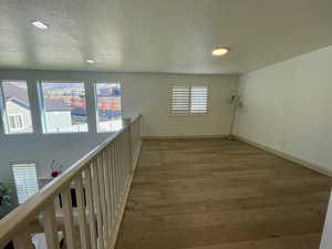 Hall featuring light wood-type flooring, plenty of natural light, and a textured ceiling