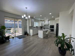 Kitchen with double oven, white cabinets, a center island, and a healthy amount of sunlight