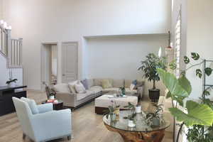 Living room with light hardwood / wood-style flooring, a chandelier, and a high ceiling