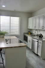 Kitchen featuring white cabinetry, sink, stainless steel appliances, and a textured ceiling