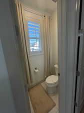 Bathroom featuring tile patterned flooring, walk in shower, and toilet