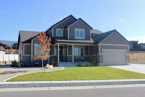 Craftsman-style house featuring a garage, a front lawn, and covered porch