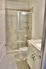 Bathroom with walk in shower, vanity, tile patterned flooring, and toilet