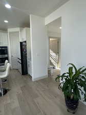 Kitchen featuring refrigerator, white cabinets, stainless steel double oven, and light hardwood / wood-style floors