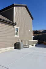 View of side of home with central air condition unit and a patio