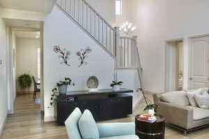 Living room with a high ceiling, hardwood / wood-style flooring, and a notable chandelier