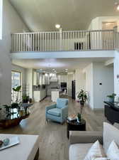 Living room featuring a high ceiling, a notable chandelier, and light hardwood / wood-style flooring