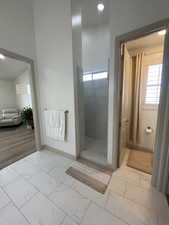 Bathroom featuring hardwood / wood-style floors, a high ceiling, and tiled shower