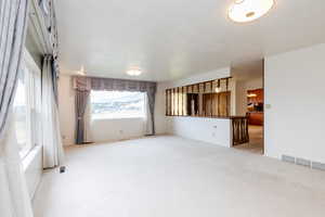 Unfurnished living room with a textured ceiling and carpet flooring