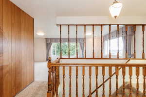 Stairs featuring carpet floors, wooden walls, and a textured ceiling