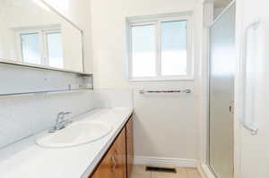 Bathroom with tile patterned flooring, a shower with door, and vanity