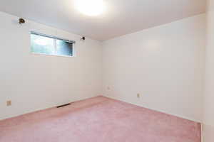 Empty room with light carpet and a textured ceiling