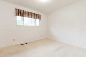 Spare room featuring vaulted ceiling and carpet flooring