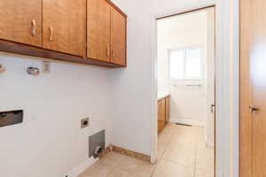 Laundry area featuring cabinets, hookup for an electric dryer, and light tile patterned flooring