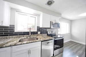 Kitchen featuring appliances with stainless steel finishes, sink, a wealth of natural light, and white cabinetry