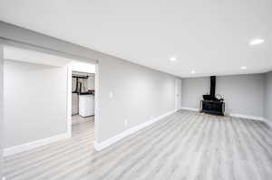 Unfurnished living room featuring a wood stove, light hardwood / wood-style floors