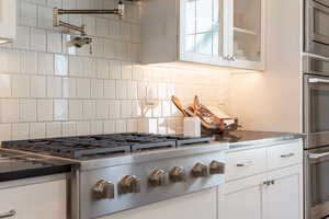 Kitchen with backsplash, stainless steel appliances, and white cabinets