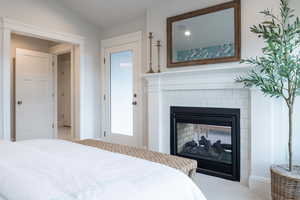 Carpeted bedroom with vaulted ceiling and a tile fireplace