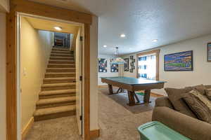 Recreation room with a textured ceiling and carpet flooring