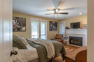 Bedroom with ceiling fan, hardwood / wood-style floors, and a tile fireplace