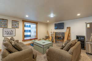 Living room featuring light carpet, a stone fireplace, and a textured ceiling