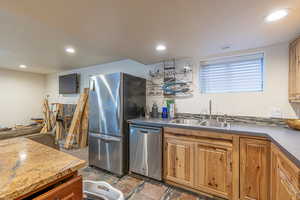 Kitchen with a textured ceiling, appliances with stainless steel finishes, tile patterned flooring, and sink