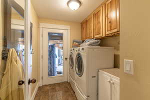 Washroom featuring washer and clothes dryer, cabinets, dark hardwood / wood-style floors, and a textured ceiling