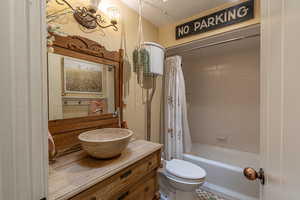 Full bathroom with shower / bath combination with curtain, vanity, toilet, and a textured ceiling