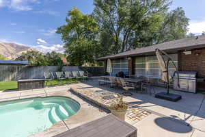 View of pool with a mountain view, a jacuzzi, area for grilling, and a patio area