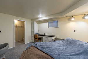 Carpeted bedroom featuring a closet, built in desk, and a spacious closet