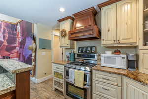 Kitchen featuring custom exhaust hood, cream cabinets, light hardwood / wood-style floors, and double oven range