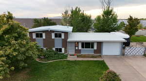 Tri-level home featuring a garage and a lawn