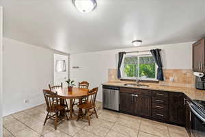 Kitchen featuring dark brown cabinetry, sink, light stone counters, decorative backsplash, and appliances with stainless steel finishes