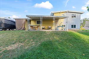 Rear view of house with a yard and a patio