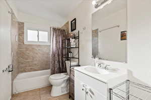 Full bathroom featuring shower / bath combination with curtain, vaulted ceiling, vanity, and toilet