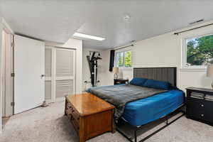 Bedroom with light colored carpet and a textured ceiling