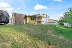 Rear view of property featuring a lawn and central air condition unit