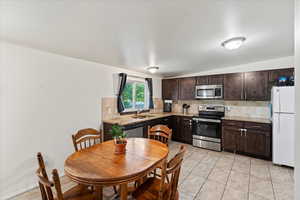 Kitchen featuring dark brown cabinets, appliances with stainless steel finishes, backsplash, and sink