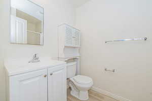 Bathroom with a shower with shower door, hardwood / wood-style flooring, vanity, and toilet