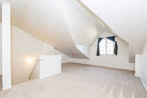 Additional living space with light colored carpet and lofted ceiling