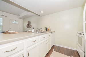 Kitchen featuring white appliances, dark wood-type flooring, sink, and white cabinets