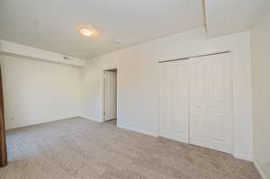 Unfurnished bedroom with a closet, a textured ceiling, and light carpet