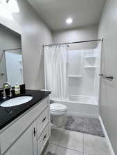 Full bathroom with shower / bath combination with curtain, vanity, toilet, and tile patterned floors