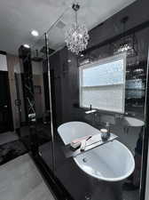 Bathroom featuring vanity, separate shower and tub, and an inviting chandelier