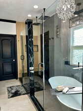 Bathroom with tile patterned flooring, a chandelier, independent shower and bath, ornamental molding, and a textured ceiling